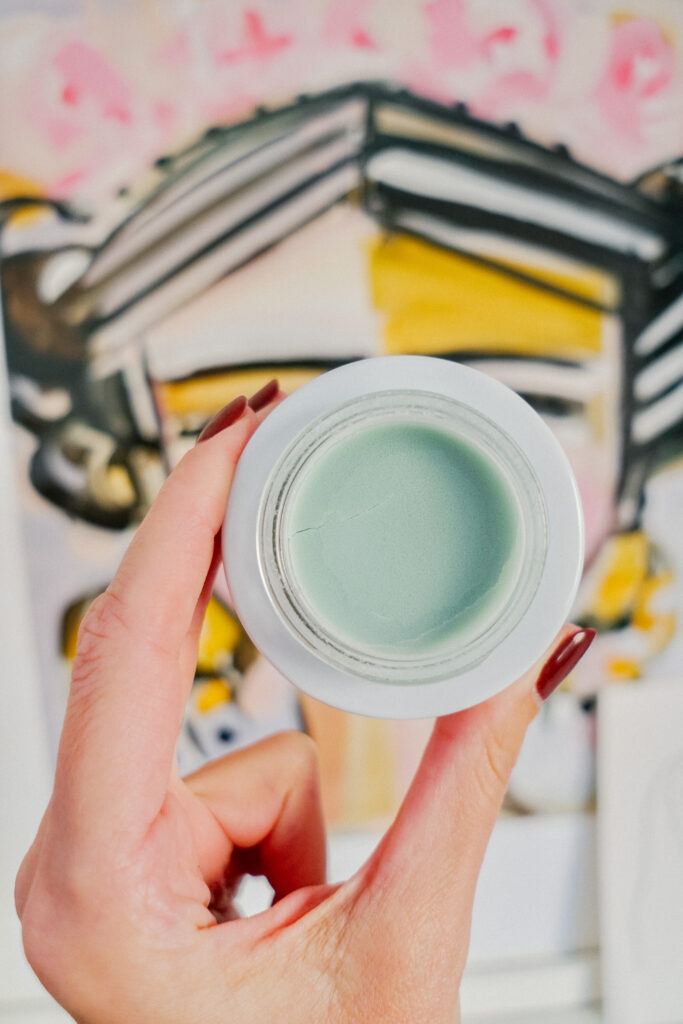 Holding up a jar of soothing summer skin care