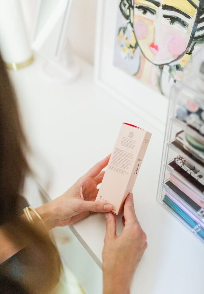 Woman reading skincare product label in store, learning how to find natural products