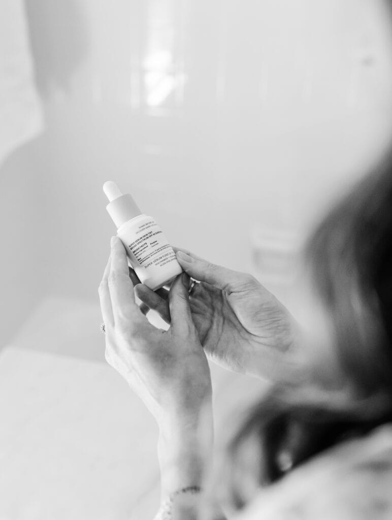 Person reading a skincare product label to check for phenoxyethanol.