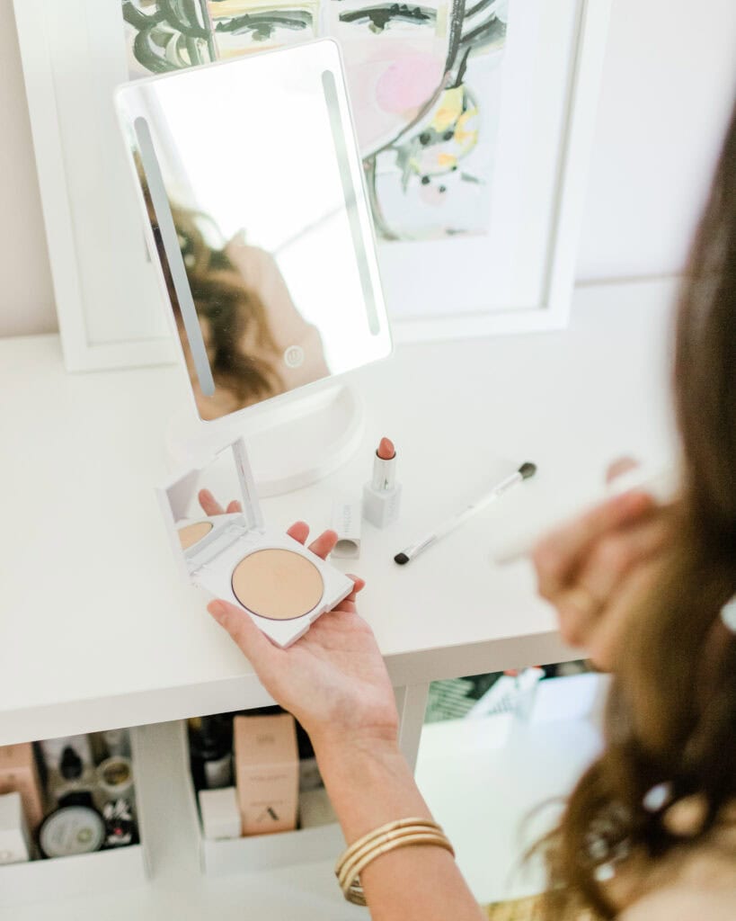Applying various makeup products at vanity
